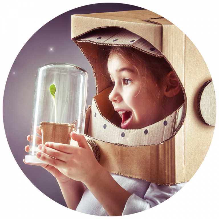 A child in a cardboard space helmet holding a seedling.