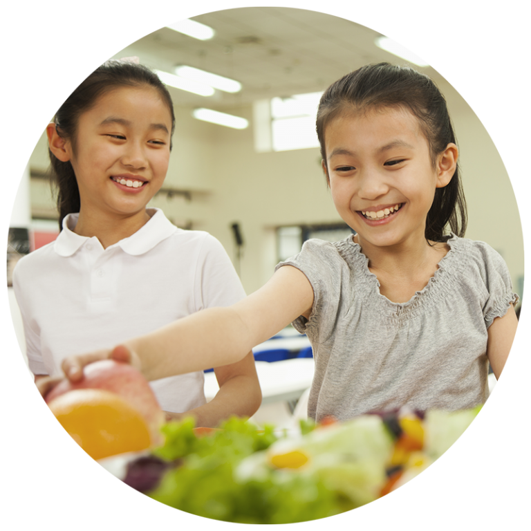 two girls choosing vegetables in the lunch line