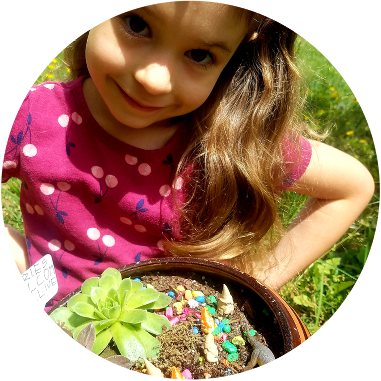 Child holding a container with small plants and fairy figures