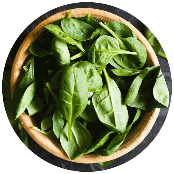 Overhead view of wooden bowl filled with spinach leaves