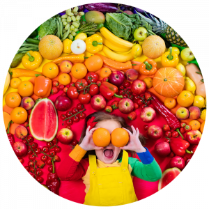 girl surrounded by a rainbow of fruits and vegetables