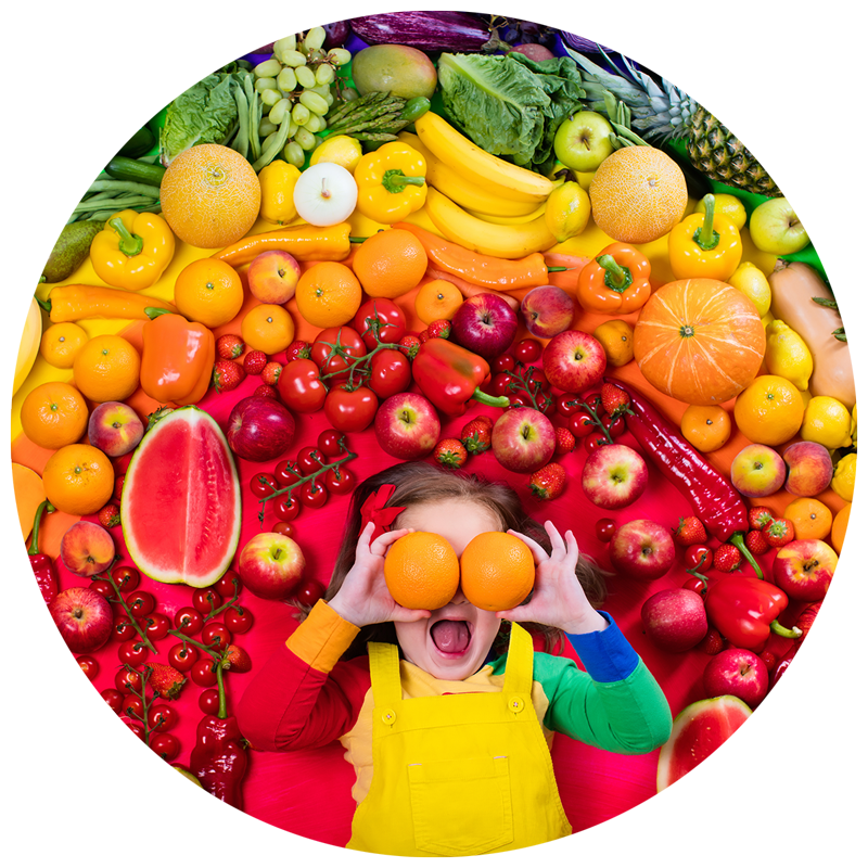 girl surrounded by a rainbow of fruits and vegetables