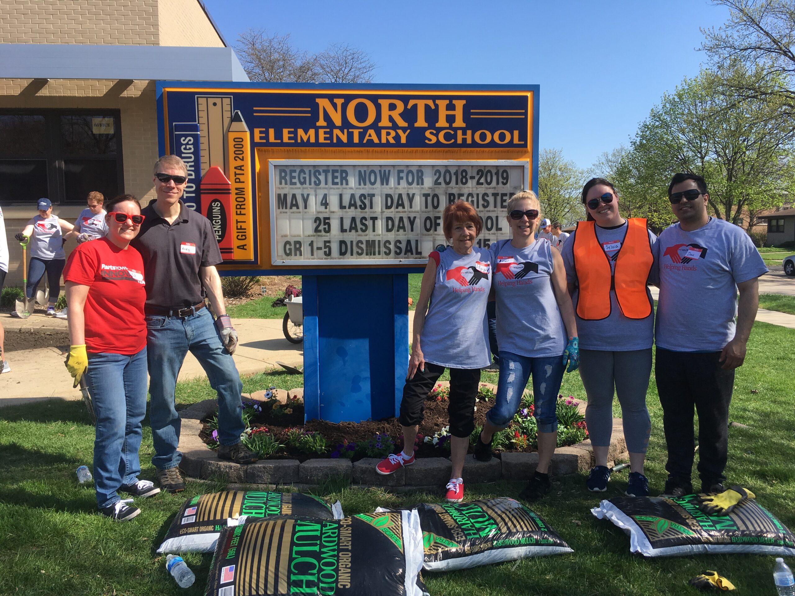 A group of adults in front of a school sign.
