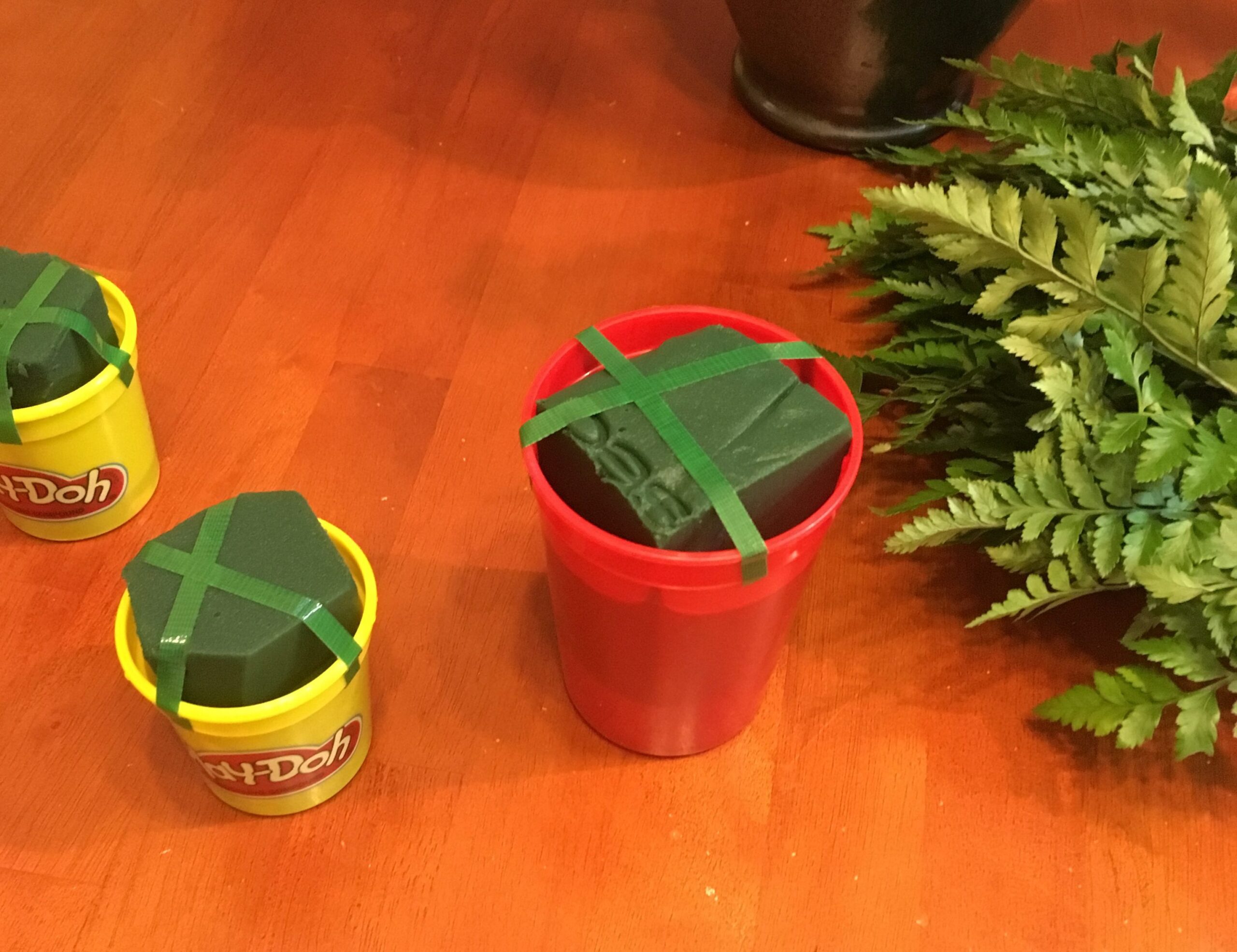 Blocks of floral foam held in recycled play dough containers with green anchor tape