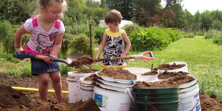 Two kids shoveling compost into a garden