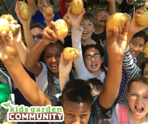 Excited kids hold up potatoes. A logo reading "kids garden COMMUNITY" is in the corner