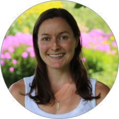 Amelia Dupuis, a white woman with brown hair smiling at camera with flowers in the background