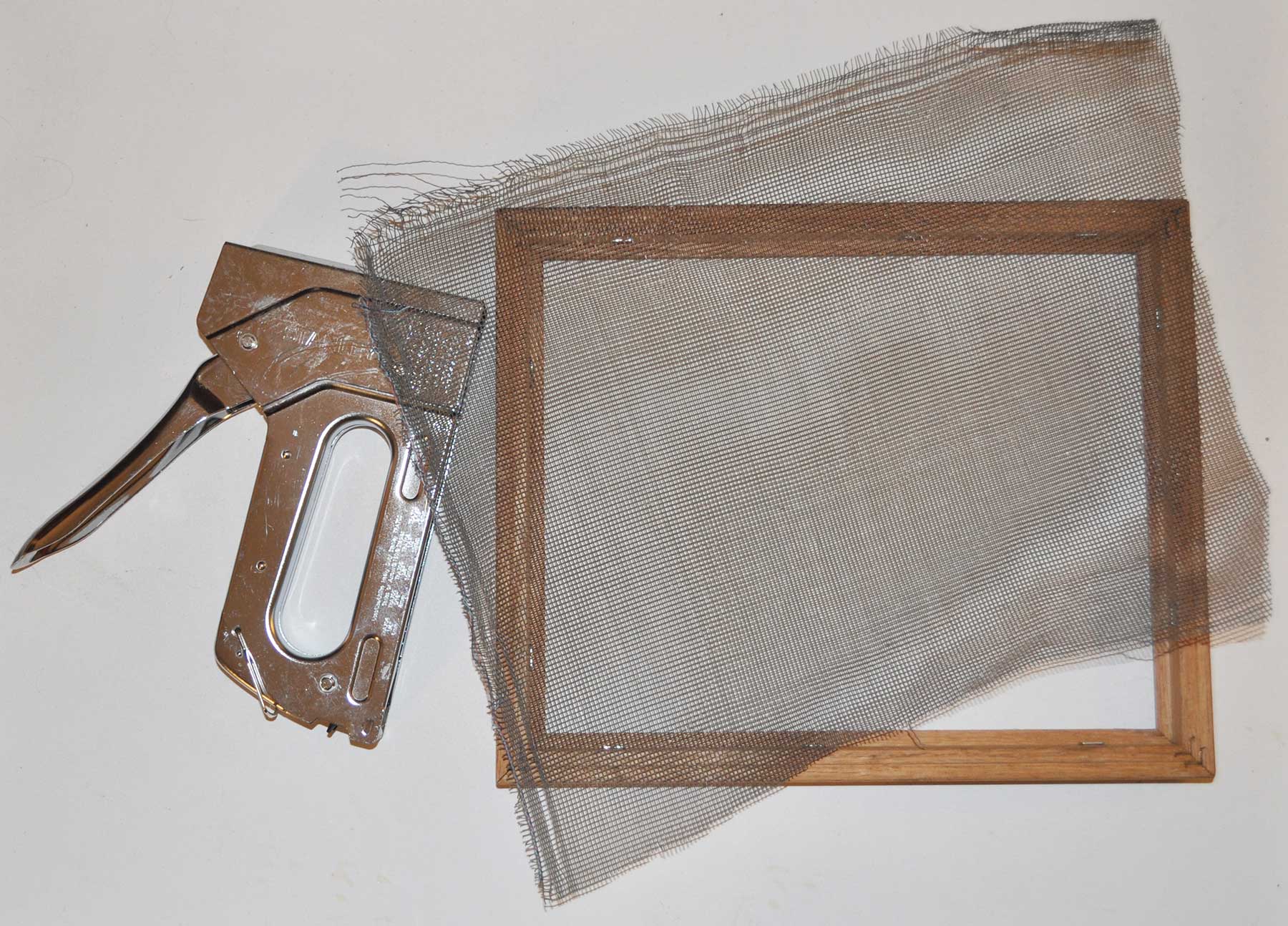 A wooden frame, a piece of window screen and a staple gun