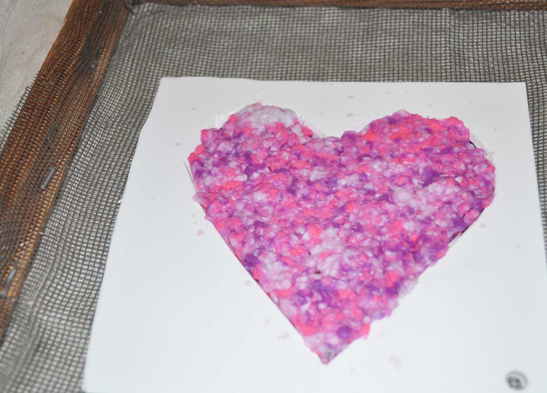 Paper pulp pressed into the heart stencil on the screen