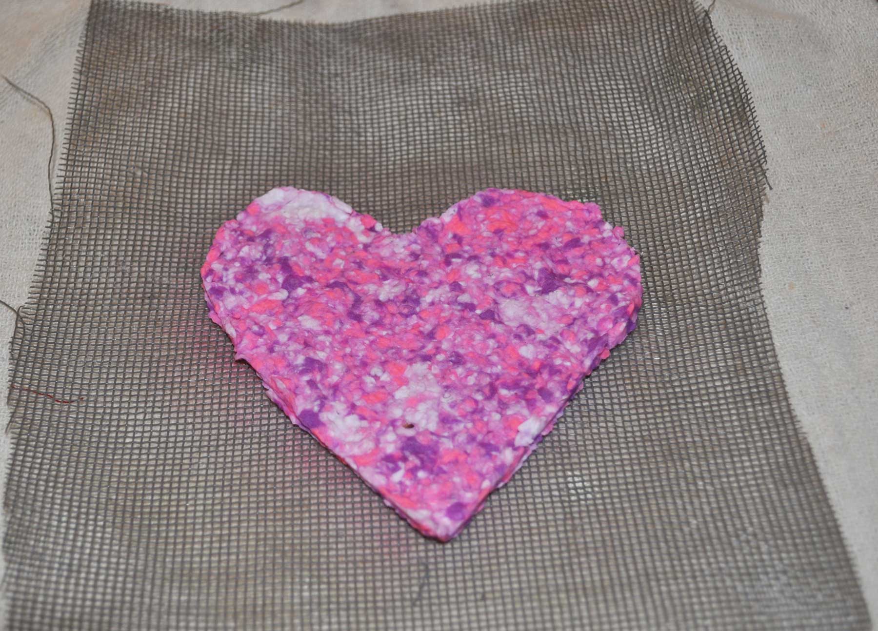 A pink and purple paper heart drying on the screen
