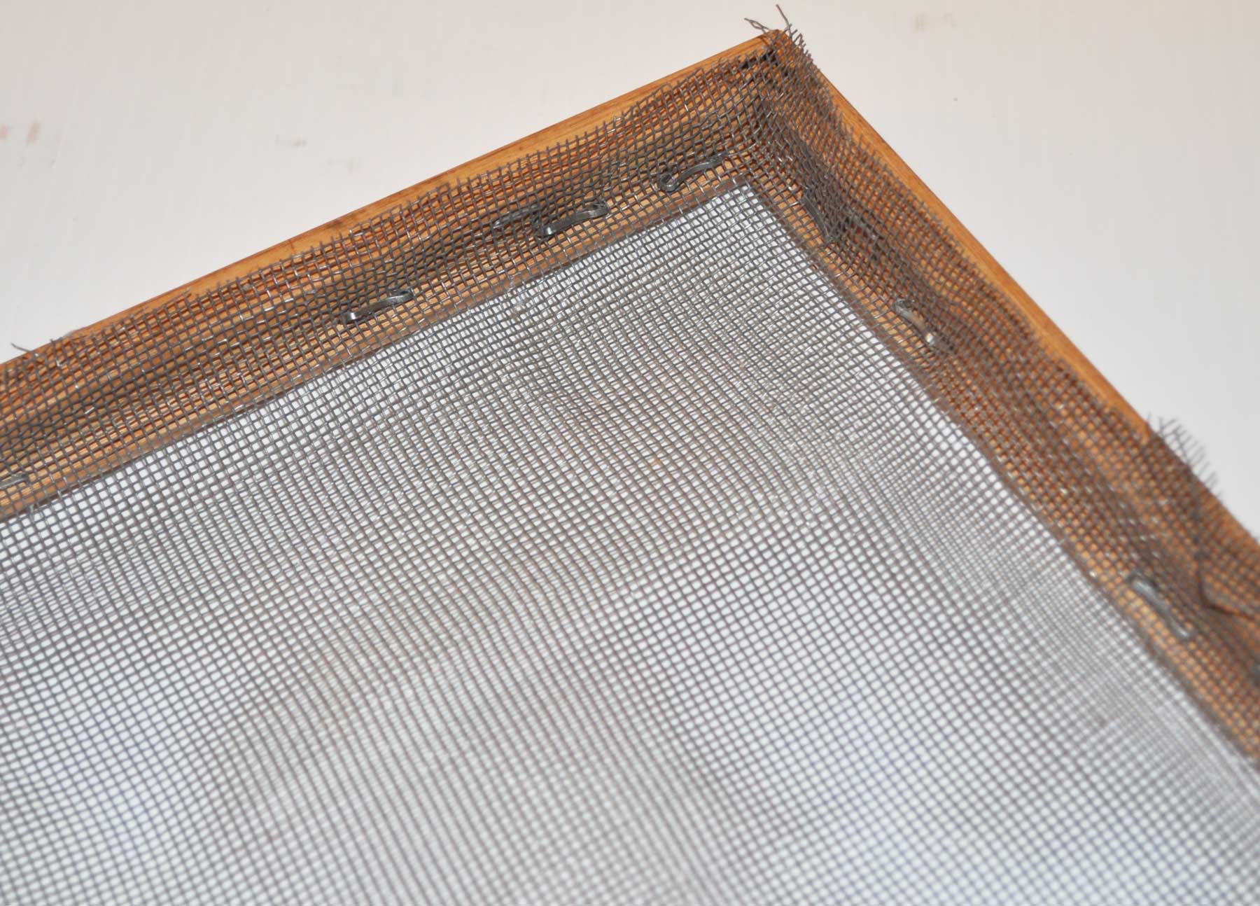 Window screen stapled tightly onto a wooden frame