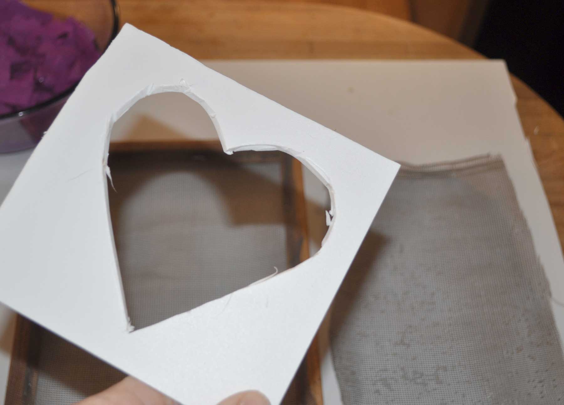 A heart shape cut out of a piece of card stock to use as a stencil