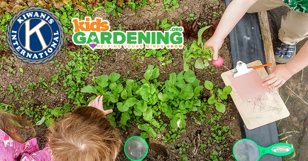 Two kids working in the garden, but you can't see their faces. The Kiwanis and KidsGardening logos are at the top