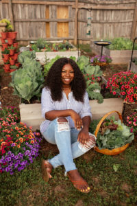 Jasmine sitting in front of a colorful raised bed garden