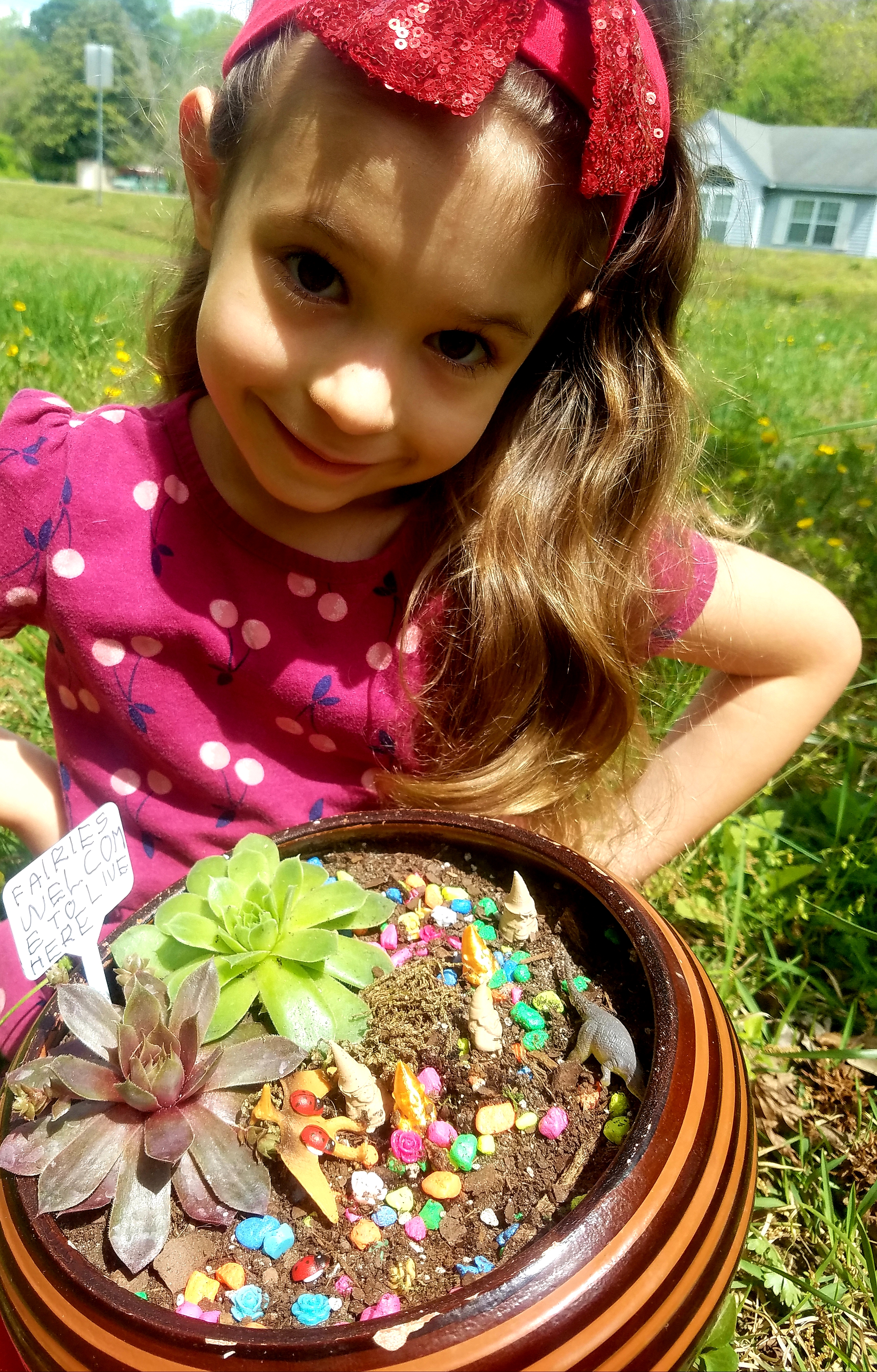 Child holding a container with small plants and fairy figures