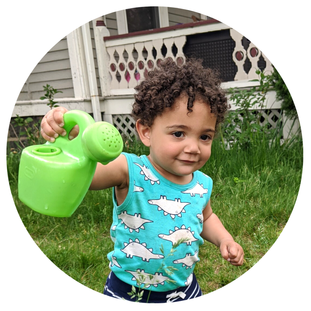 A young child holding a green plastic watering can