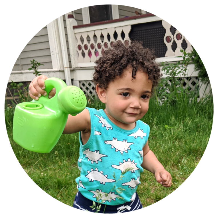 A young child holding a green plastic watering can