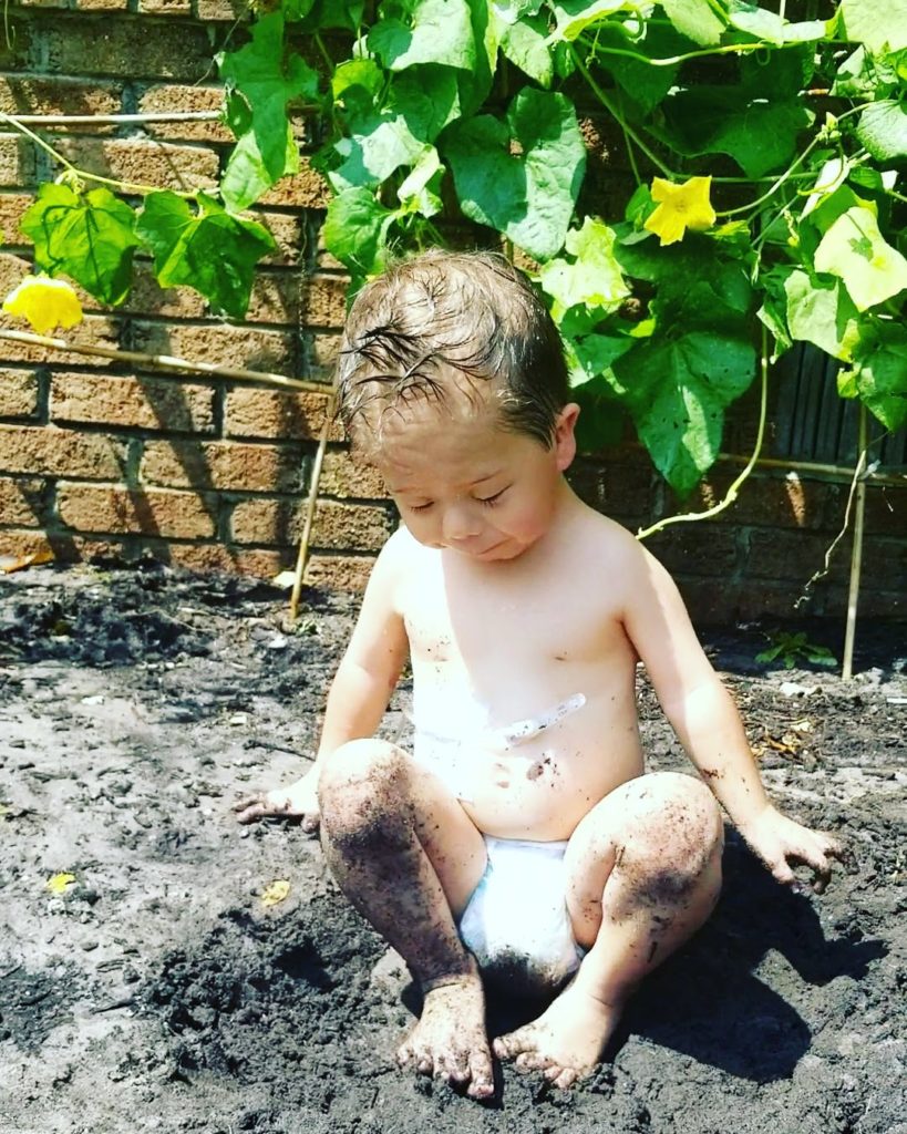 A child sitting in the soil in a garden