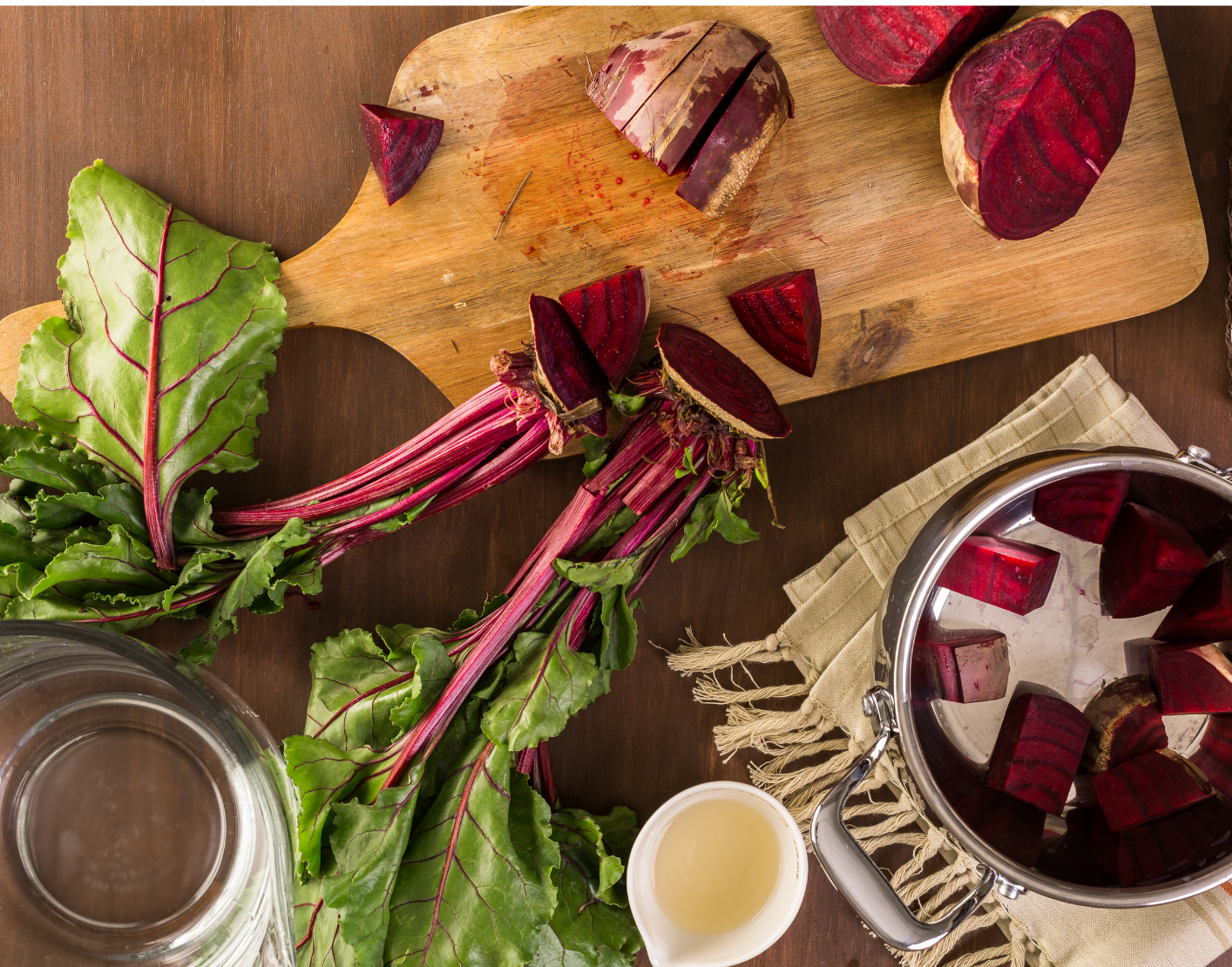 Chopped beets and beet greens on a cutting board, with a bowl of beets nearby