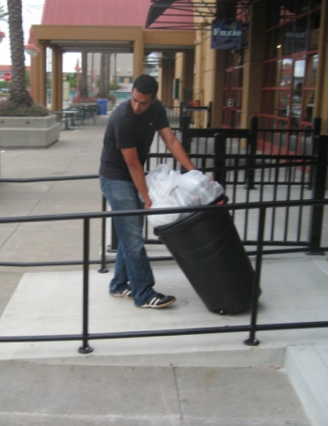Nikhil Arora, picking up coffee grounds in a trash can