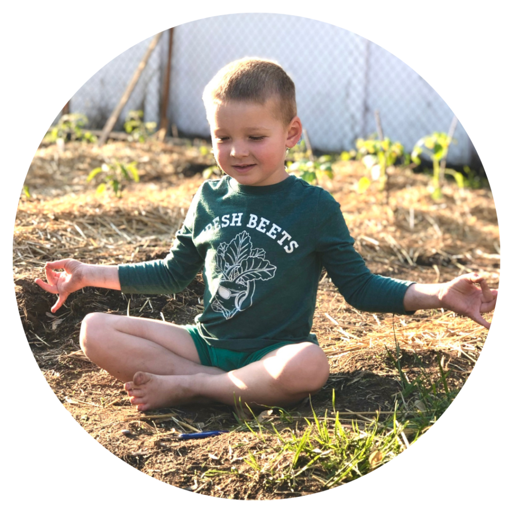 A child sitting with crossed legs and their arms out in a meditative pose