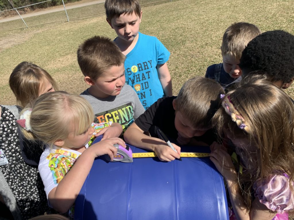 Kids surround a blue plastic barrel