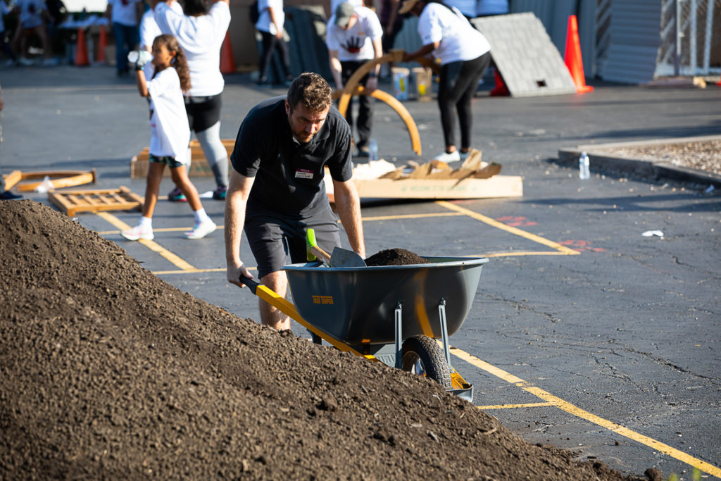 A person pushing a wheelbarrow full of soil