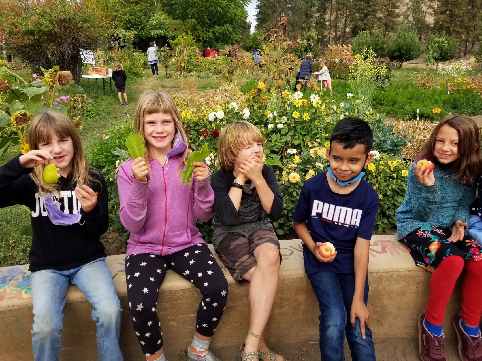 Kids holding up lettuce in front of a garden