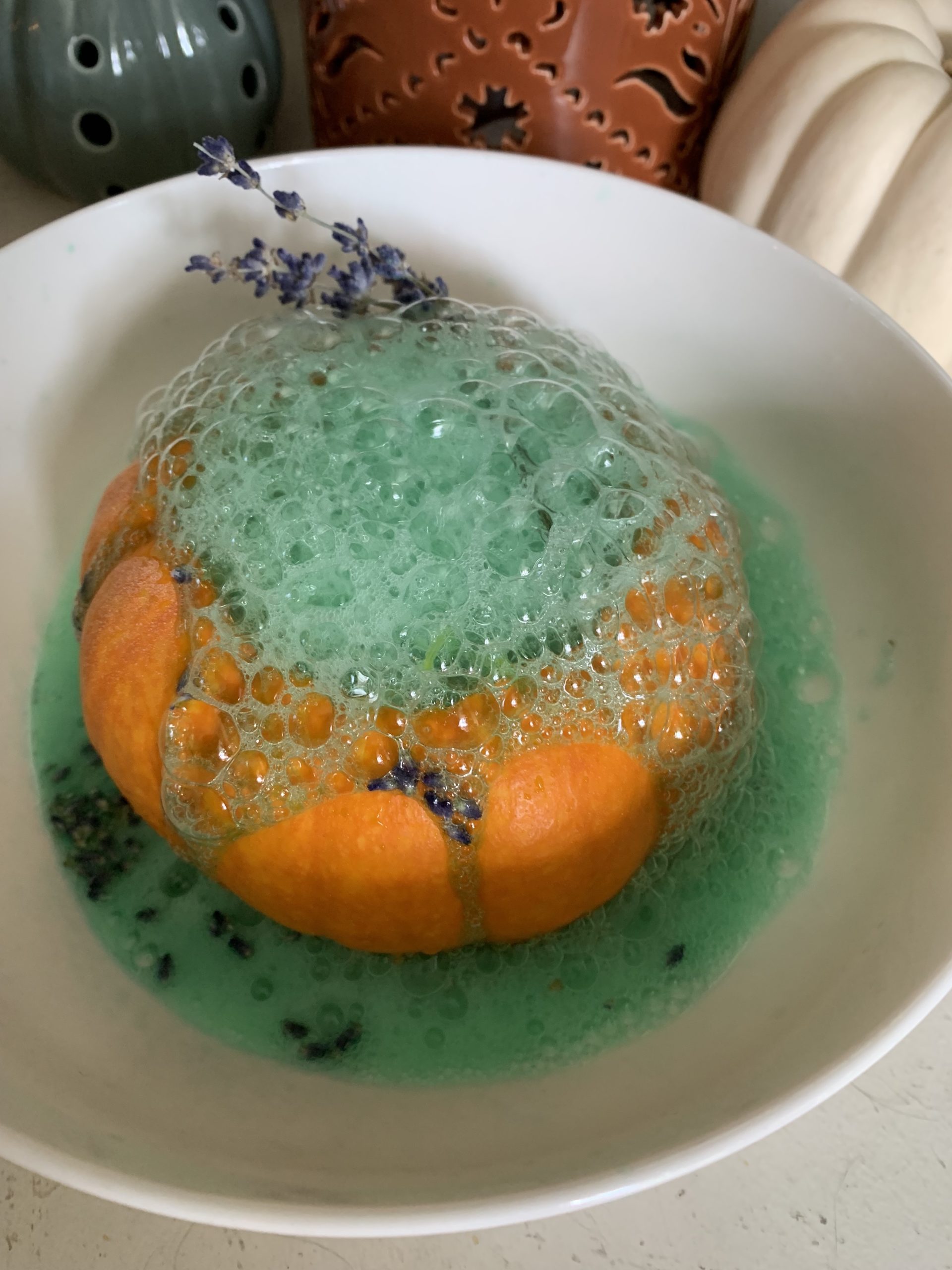 A pumpkin with green foam coming out of the top