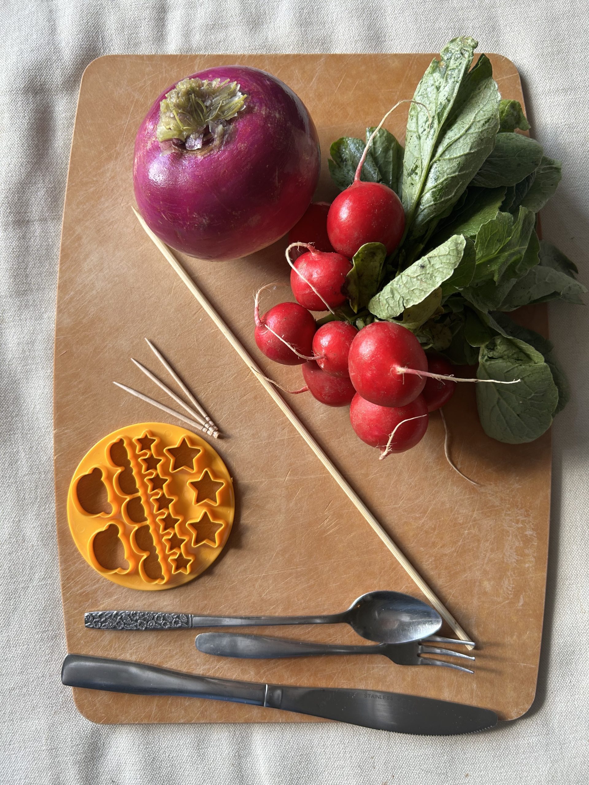 Vegetables and cookie cutters laid out artisticly on a cutting mat