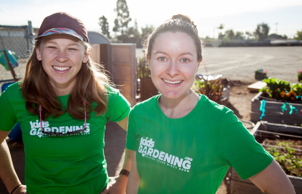 Two people wearing green shirts with the KidsGardening logo.