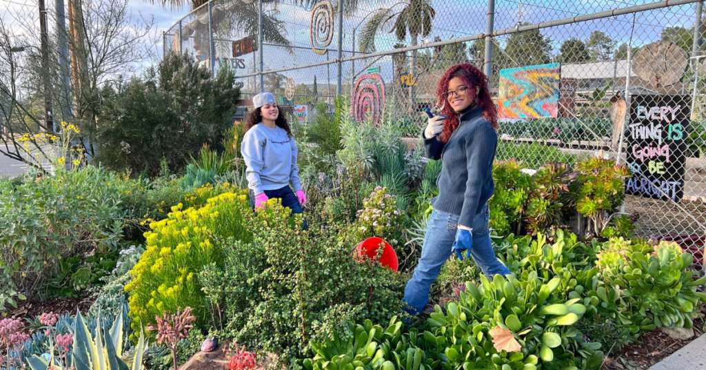 Two people in a lush garden looking back at the camera