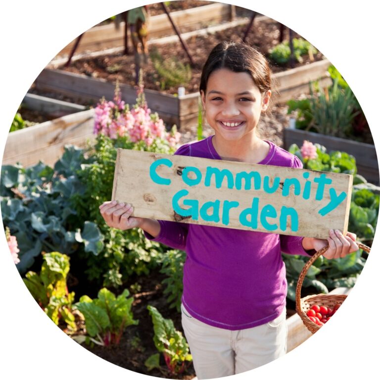 A child in a purple shirt holds up a painted wooden sign that reads Community Garden