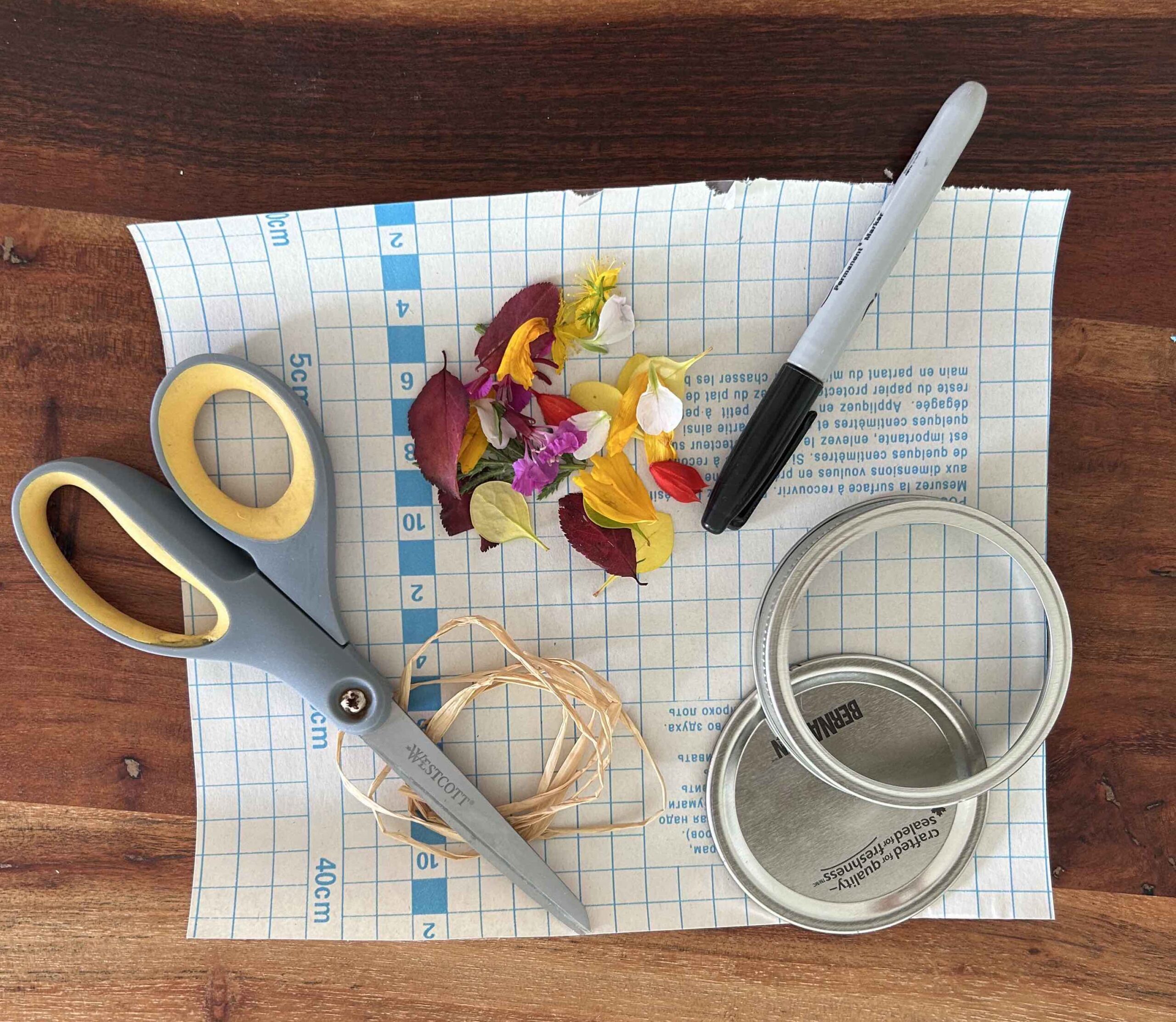 Scissors, flower petals, a marker, jar lid, and jar ring.