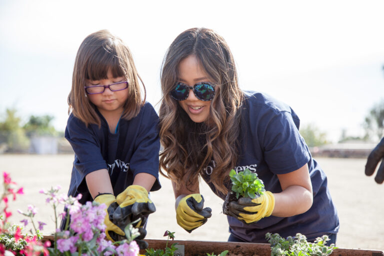 An adult and a child work together in a garden