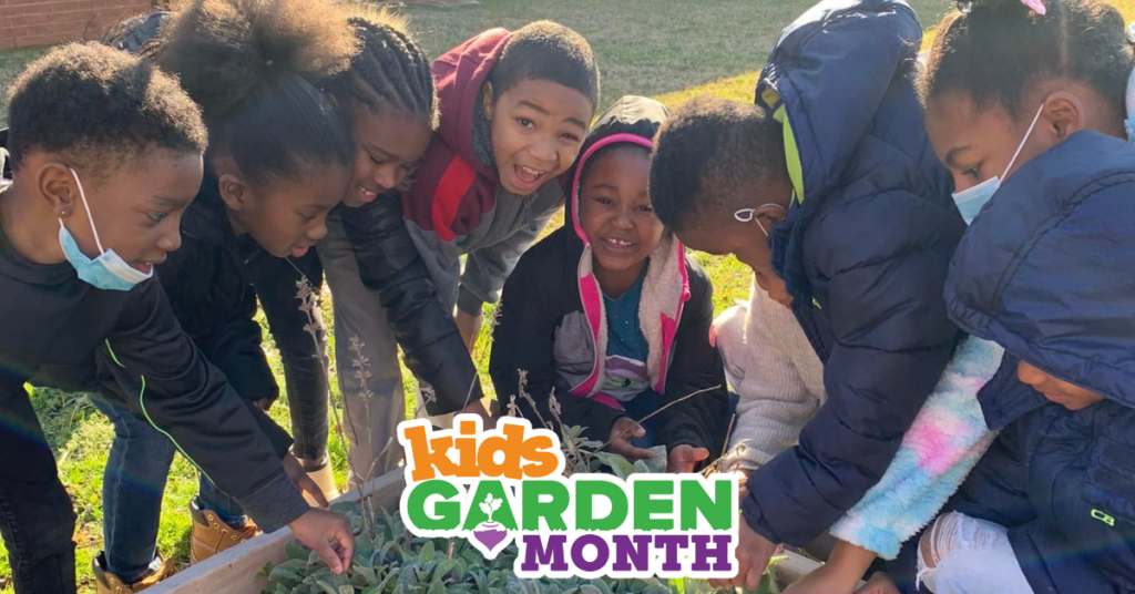 A group of kids gathered around a raised bed. They are wearing winter coats and a few are wearing face coverings. A logo that reads Kids Garden Month is at the bottom.