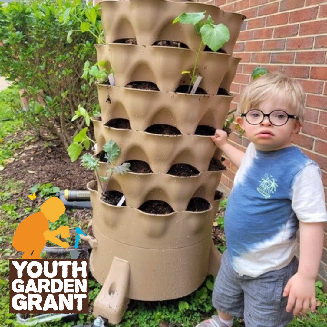 A child in glasses next to a tower garden. The Youth Garden Grant logo is in the corner.