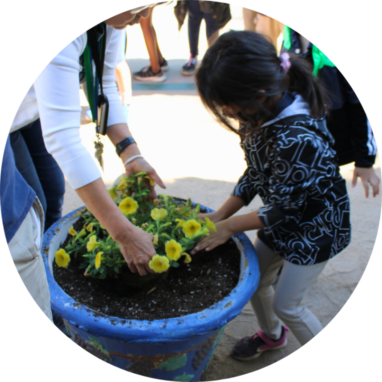 An adult and a child planting in a blue container
