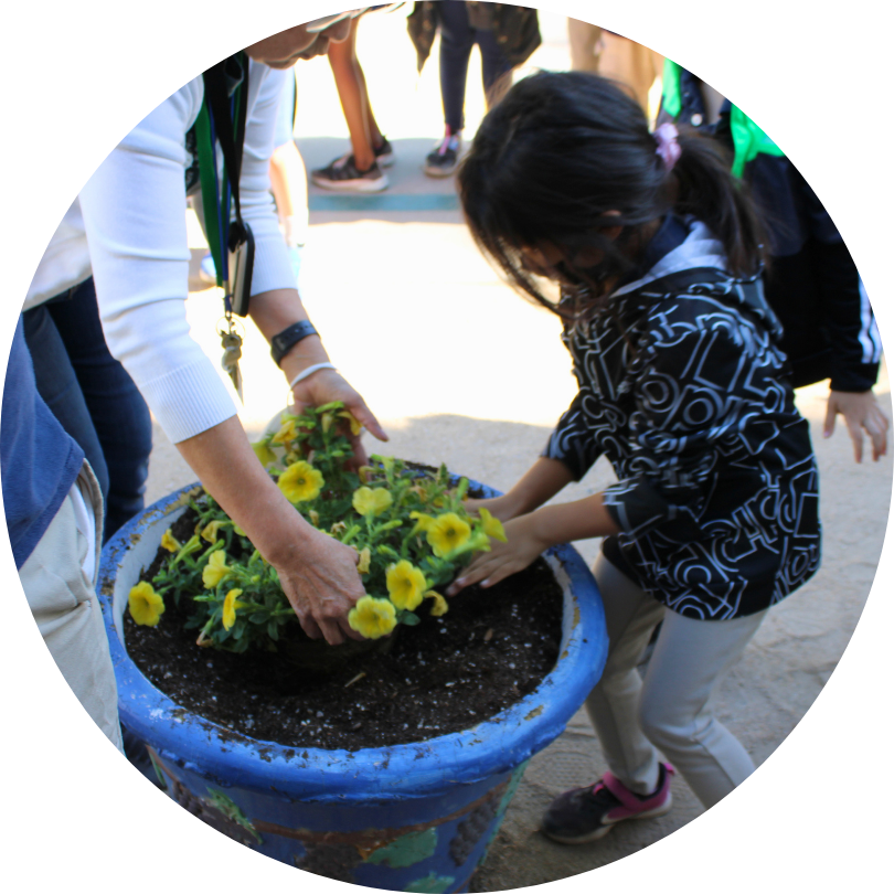 An adult and a child planting in a blue container