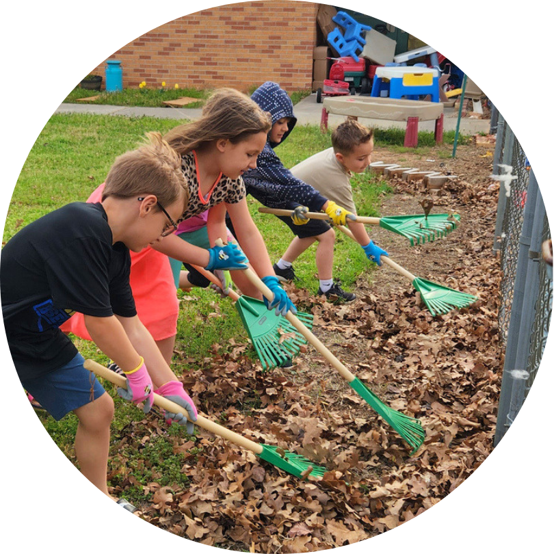 Kids in a row, raking leaves with different tools
