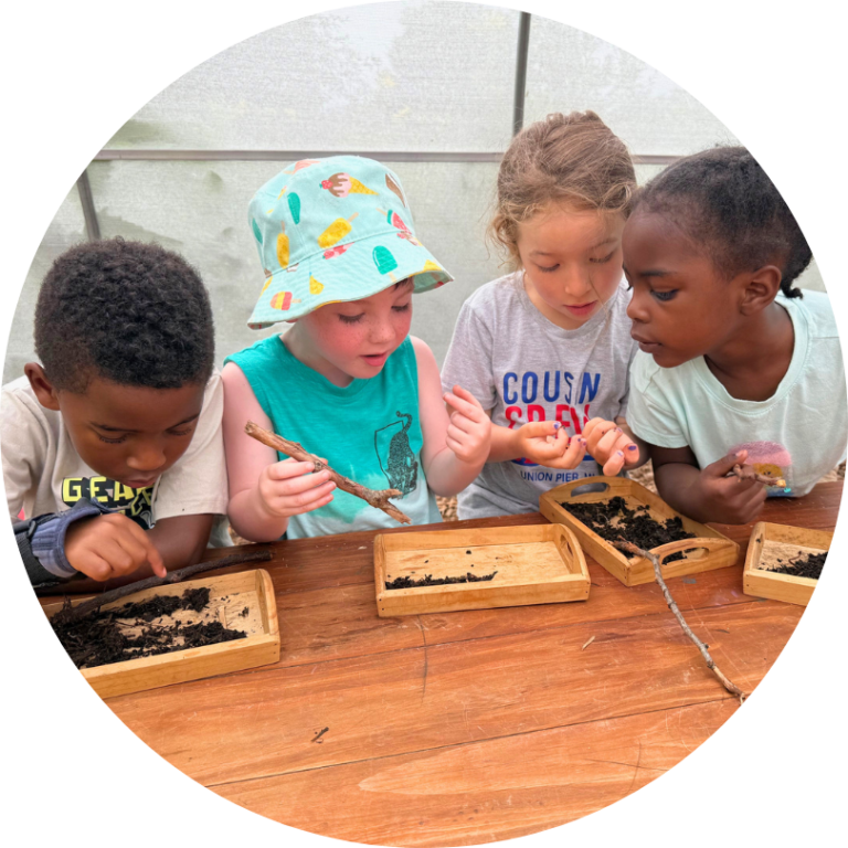 Four kids sitting at a table looking at seeds and other plant materials