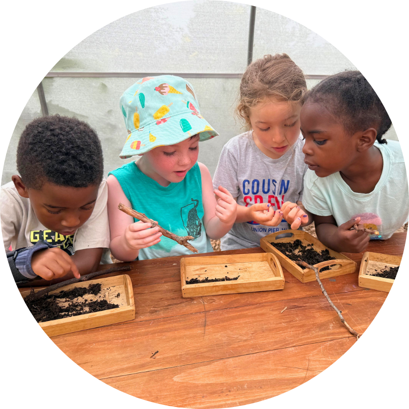 Four kids sitting at a table looking at seeds and other plant materials