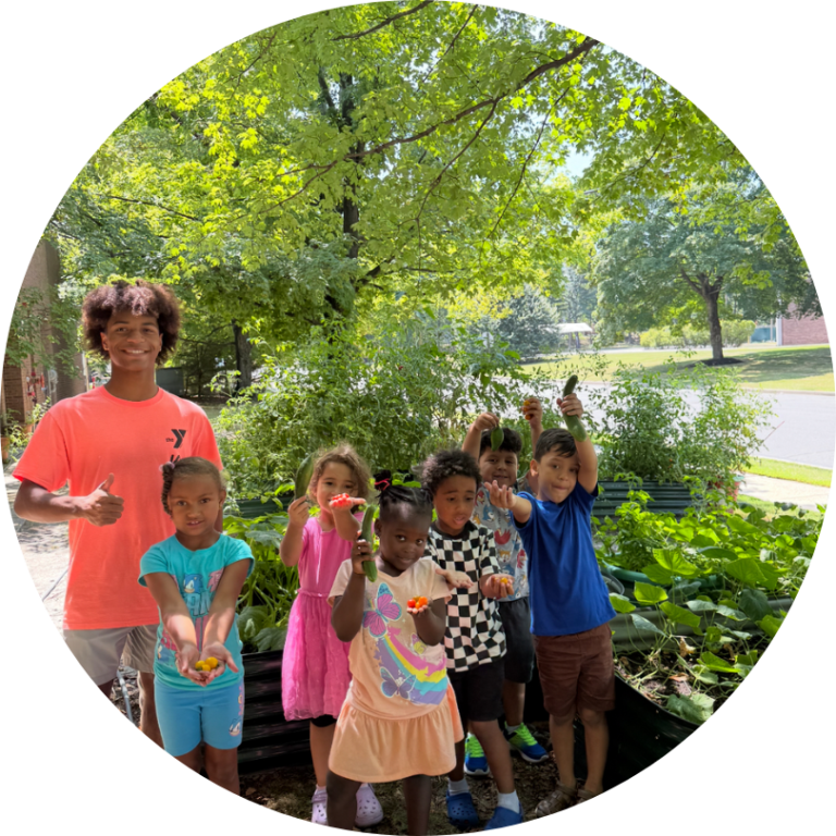 An adult and a group of children outside in front of a tree