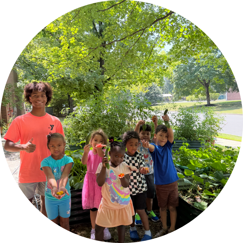 An adult and a group of children outside in front of a tree