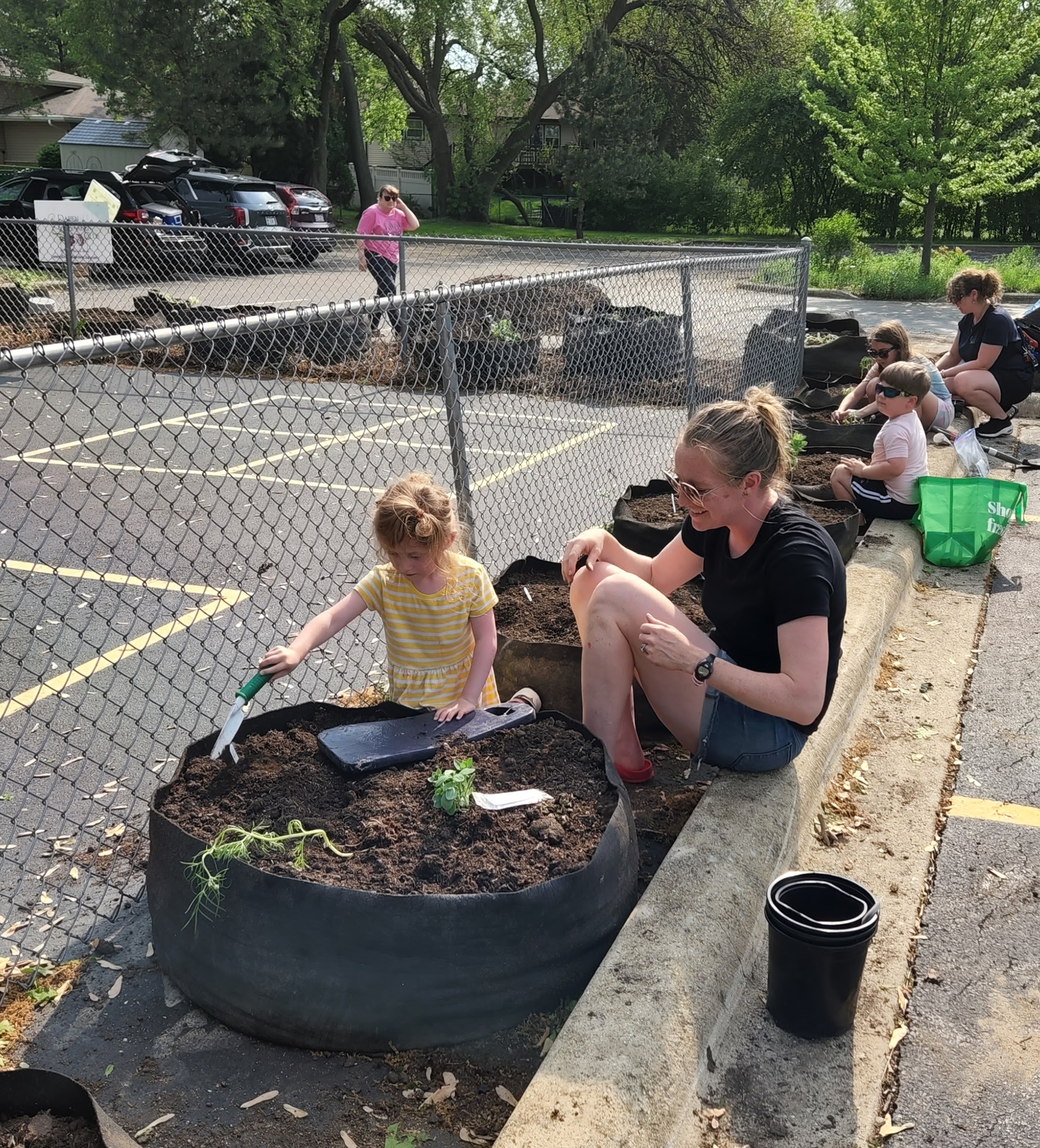 An adult and children gardening in a circular fabric raised bed.