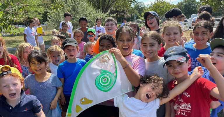 Kids outside in a garden, happily waving a handmade flag