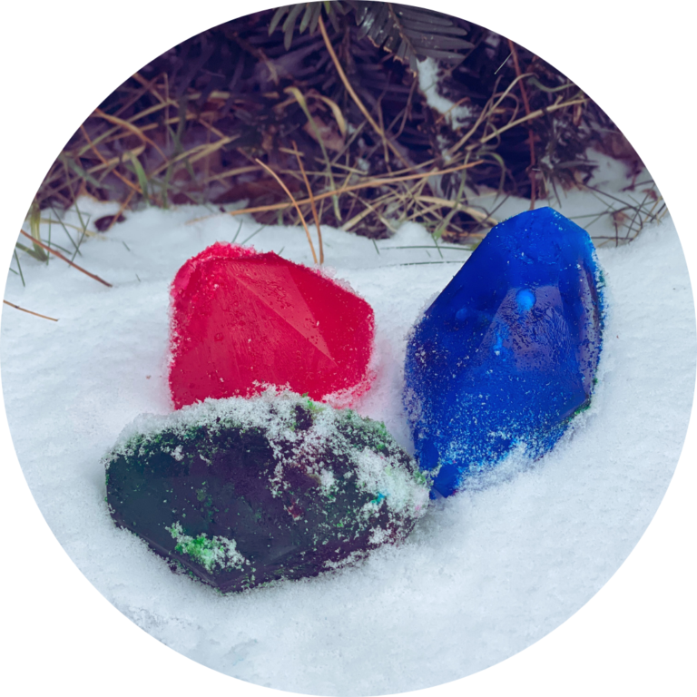 Colorful, frozen ice cubes in the shape of gemstones sit in the snow