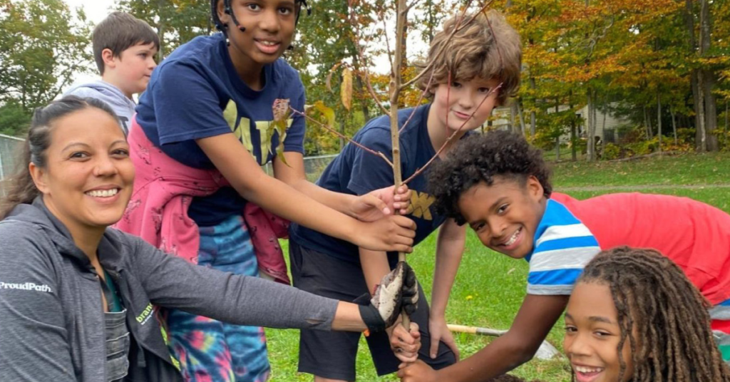 Kids and an adult planting a tree together