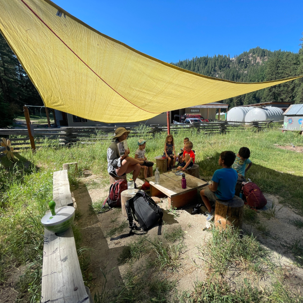 A yellow sail that is elevated and providing shade to the people sitting underneath.
